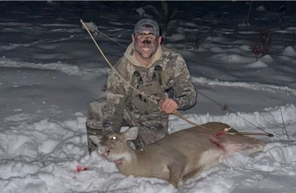 A hunter with a harvested doe in the snow